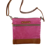A pink and waxed canvas Ellis River Crossbody Bag by Rogue Industries on a white surface.
