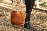 A woman holding a Rogue Industries Fore Street Tote Bag in the woods.
