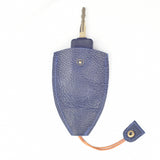 A car key with a black head is partially inserted into a Rogue Leather Key Protective Case by Rogue Industries, which has an orange string with a snap button closure.