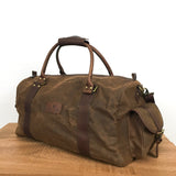 A brown White Cap waxed canvas duffle bag by Rogue Industries on a wooden table.