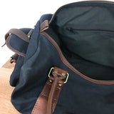 A White Cap Waxed Canvas Duffle bag by Rogue Industries on a wooden table.