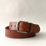 A handmade Brown Cowhide Leather Baxter Belt - 1.5" Wide by Rogue Industries on a white background.