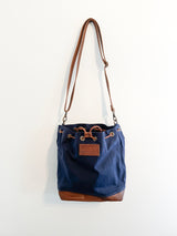 A blue Rogue Industries Kennebunkport Bucket Bag hanging on a wall.