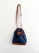 A Made-to-Order Rogue Industries Kennebunkport Bucket Bag hanging on a wall.