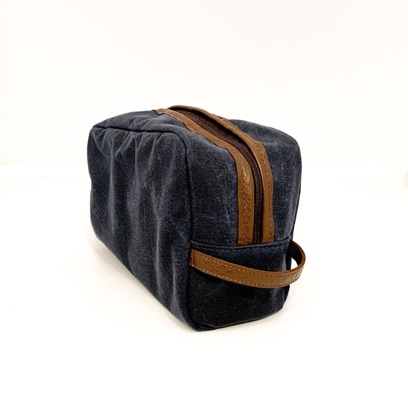 A durable, blue and tan Rogue Industries Waxed Canvas Dopp Kit made in USA on a white surface.
