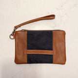 A tan and blue Eastport Clutch waxed canvas zippered pouch with a leather strap from Rogue Industries.