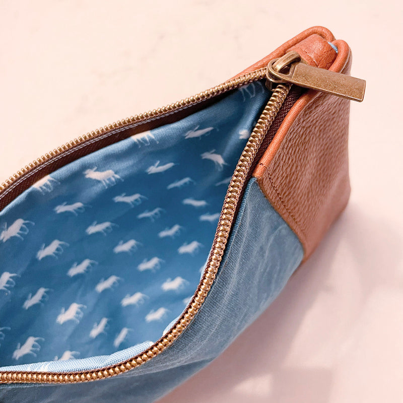 A blue and tan leather Eastport Clutch by Rogue Industries on a white surface.