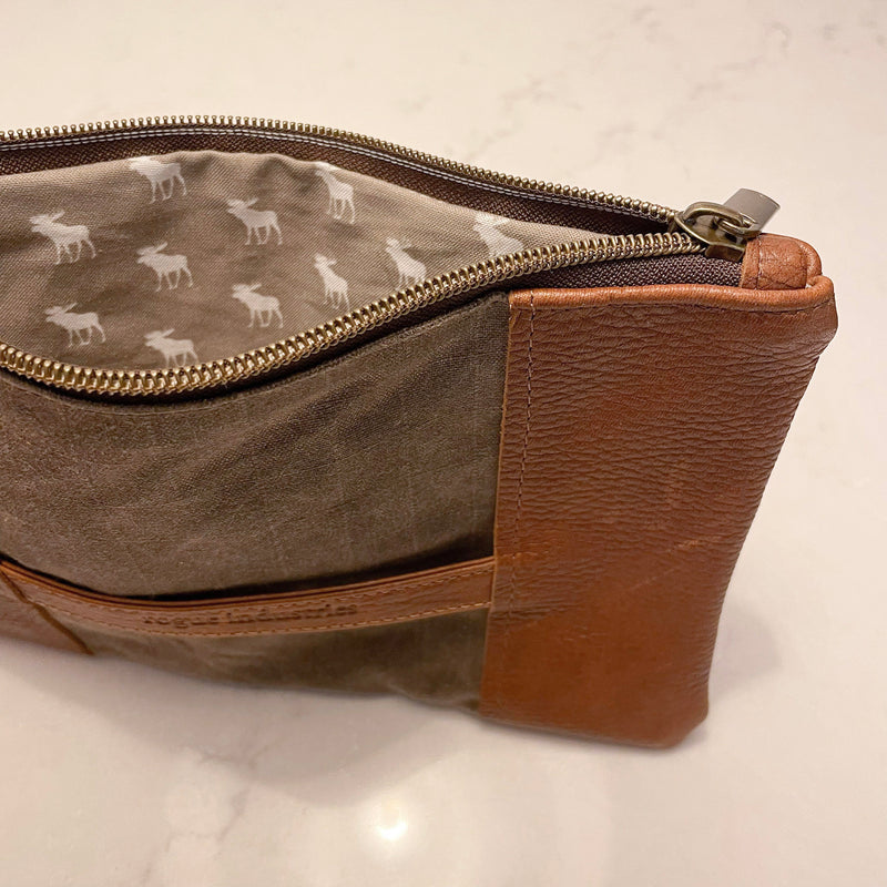 A brown and tan waxed canvas pouch with a deer on it, the Eastport Clutch by Rogue Industries.