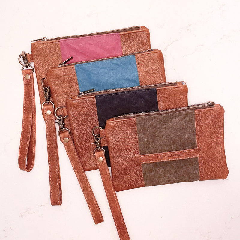 Four different colored Eastport Clutches by Rogue Industries on a white surface.