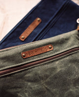 A blue and brown waxed canvas Ellis River Crossbody Bag with a cowhide leather strap by Rogue Industries.