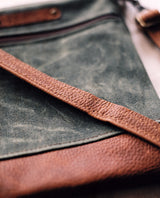 A green and brown waxed canvas and cowhide Rogue Industries Ellis River Crossbody Bag.