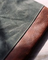 A close up of a green and brown cowhide leather Rogue Industries Ellis River Crossbody Bag.