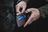 A man is holding a Rogue Industries NFL leather front pocket wallet with an RFID-blocking credit card in it.