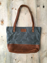A Saco River Tote Bag by Rogue Industries on a wood surface.