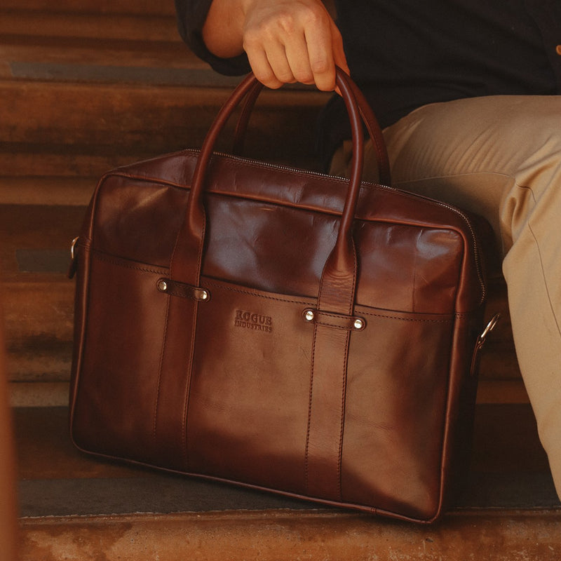 A man holding a brown, Rogue Industries Katahdin Leather Briefcase.