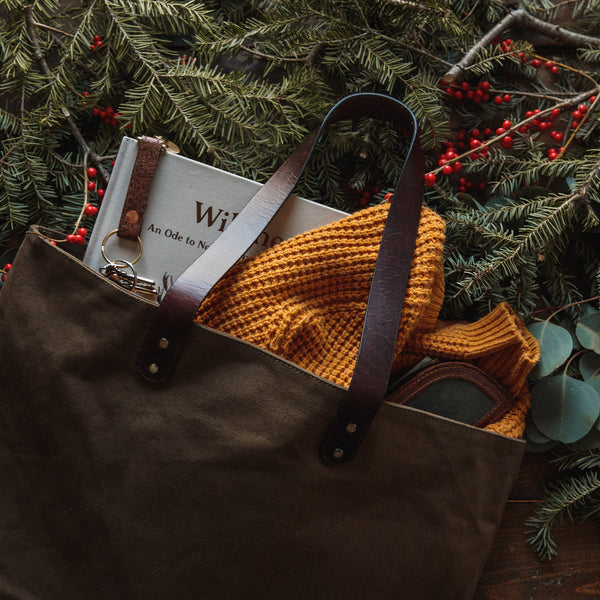 A durable, brown Rogue Industries waxed canvas tote bag with top-grain leather straps.