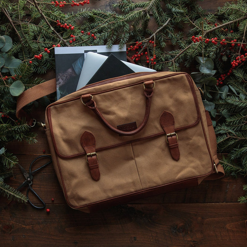 A durable waxed canvas laptop bag from Rogue Industries with a pair of scissors and a book on a table.