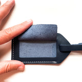 A person holding a blue Rogue leather luggage tag Made in Maine.
