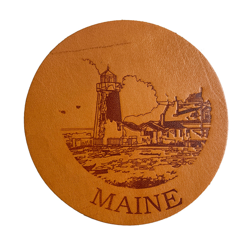 A round leather coaster with the Maine lighthouse on it is the Maine Lighthouse Coaster Set by Rogue Industries.