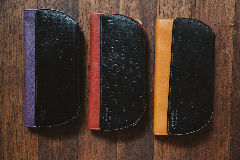 A group of Rogue Industries RFID Blocking Clutch - Ostrich Print cases on a wood surface.