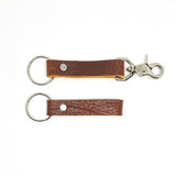 A pair of Rogue Industries brown leather keychains with nickel rivet on a white background.