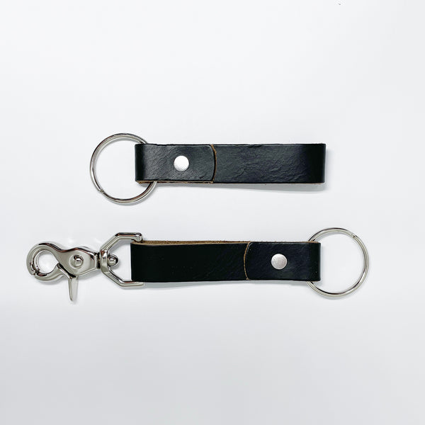 Two durable Rogue Industries black leather keychains on a white surface.