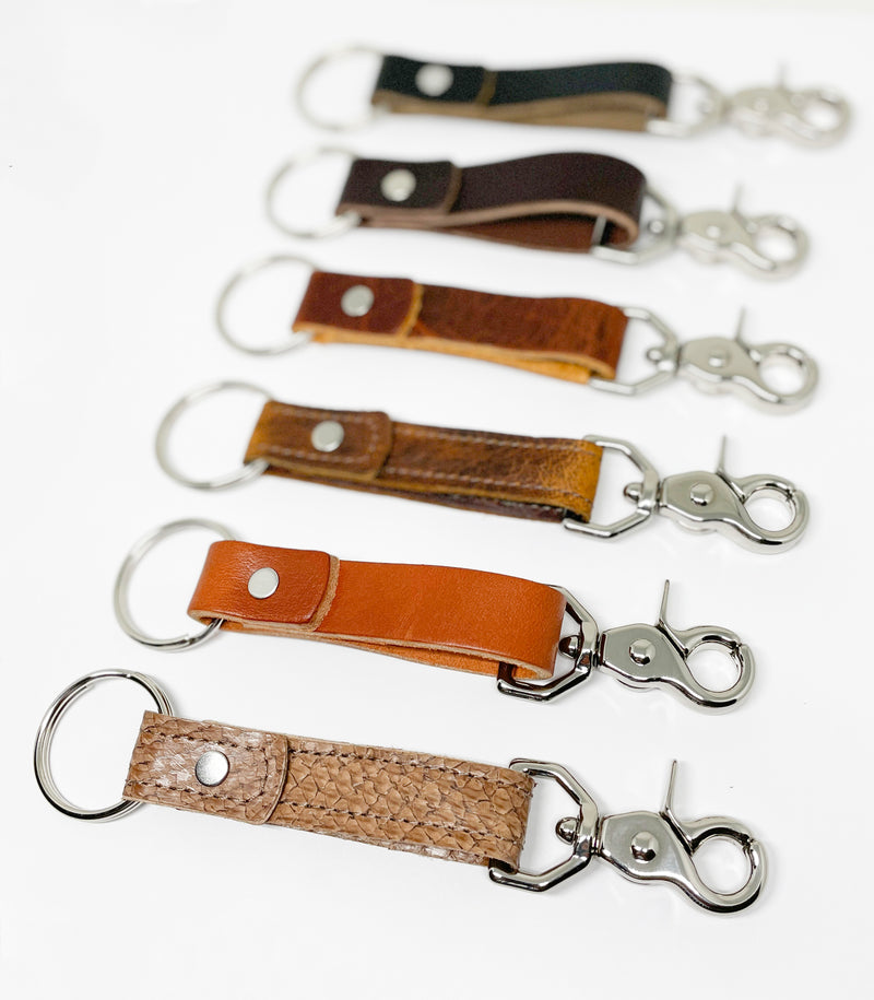 A row of different colored, Rogue Industries Leather Key Chains on a white surface.