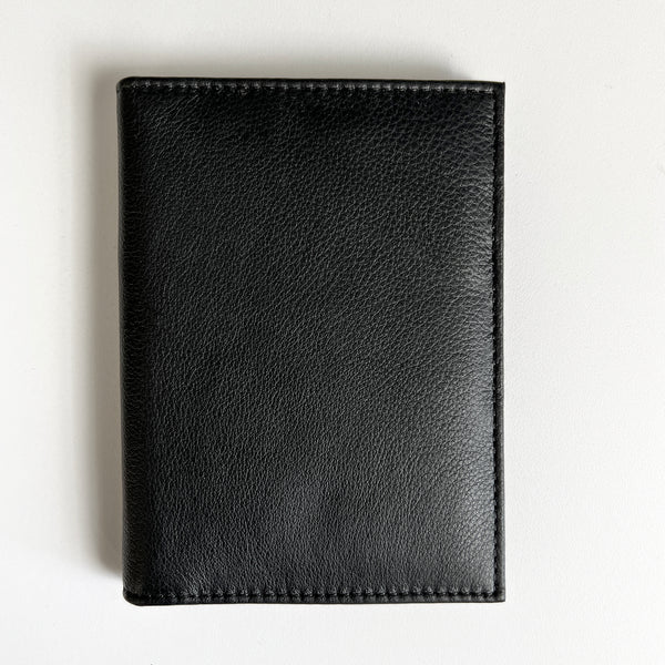 A black leather Rogue Industries passport holder with monogramming on a white surface, perfect for travelers.