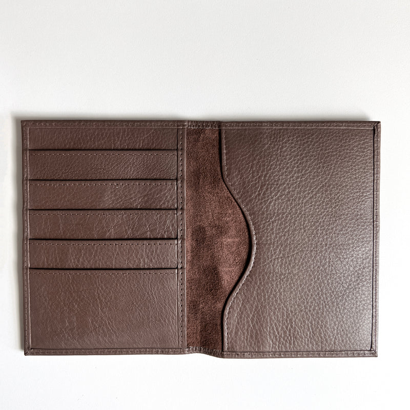 A monogrammed Rogue Industries brown leather passport holder on a white surface, perfect for travelers.