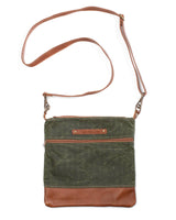 A green waxed canvas Ellis River crossbody bag with brown cowhide straps by Rogue Industries.