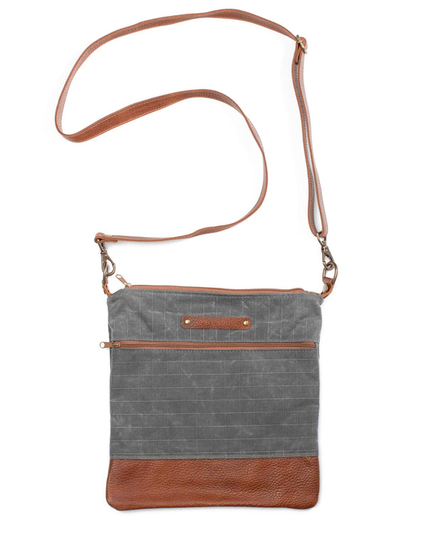 A grey waxed canvas Ellis River Crossbody Bag with brown cowhide straps by Rogue Industries.