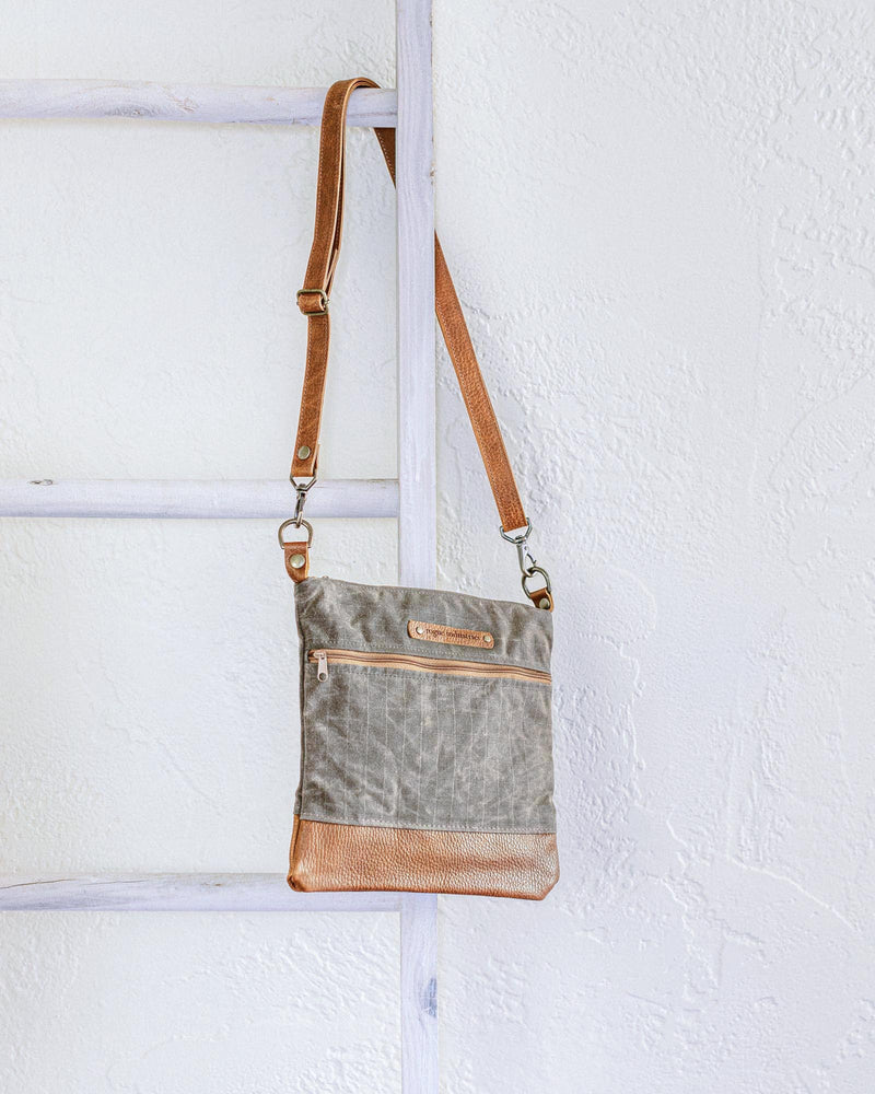 A small Ellis River Crossbody Bag by Rogue Industries hanging on a ladder.