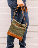 A woman holding a green and tan Rogue Industries Ellis River Crossbody Bag.