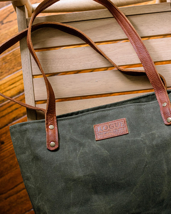 A durable, green Rogue Industries Allagash River Tote Bag sitting on a wooden chair.