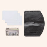 A black Rogue Industries Chamberlain Belt and Minimalist Wallet Bundle with a dollar bill and a credit card.