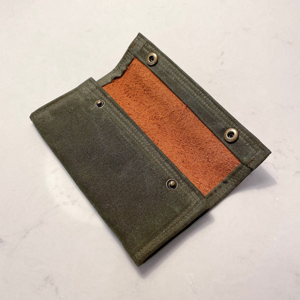 A Rogue River Fly Fishing Wallet on a white surface, designed for a fishing trip with a compartment for flies.