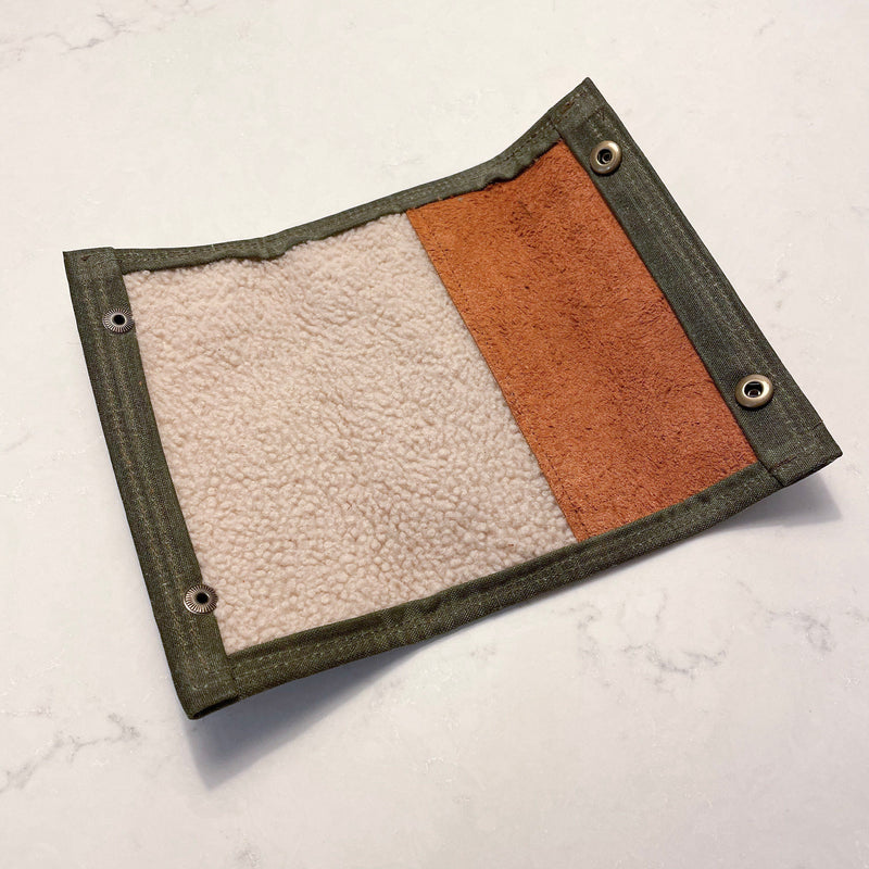 A Rogue Industries Rogue River Fly Fishing Wallet in green and tan waxed canvas on a white surface.