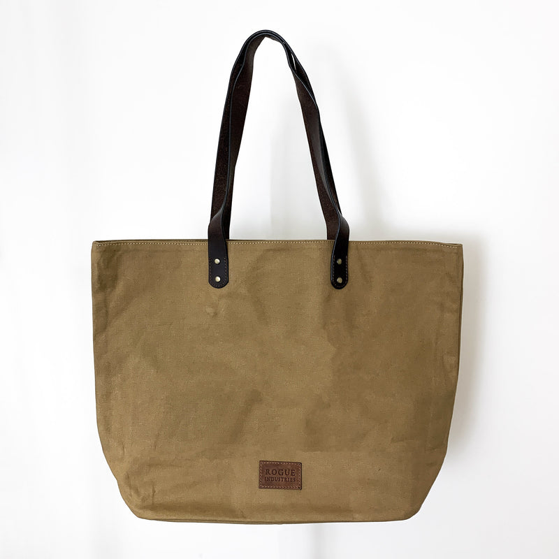 A durable, tan Rogue Industries waxed canvas tote bag with top-grain leather straps.