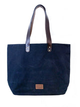A black Rogue Industries waxed canvas tote bag with top-grain leather straps.