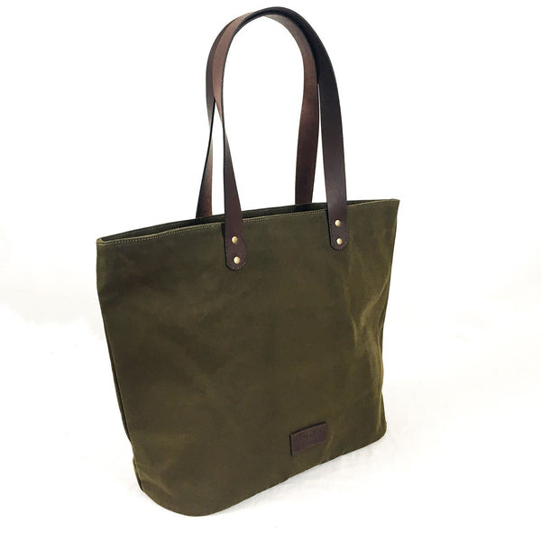 A green Rogue Industries waxed canvas tote bag with brown top-grain leather straps.