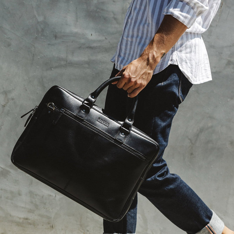 A man carrying a West End Slim Leather Laptop Bag by Rogue Industries with a removable strap.