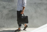 A man walking with a black, genuine leather West End Slim Laptop Bag by Rogue Industries.