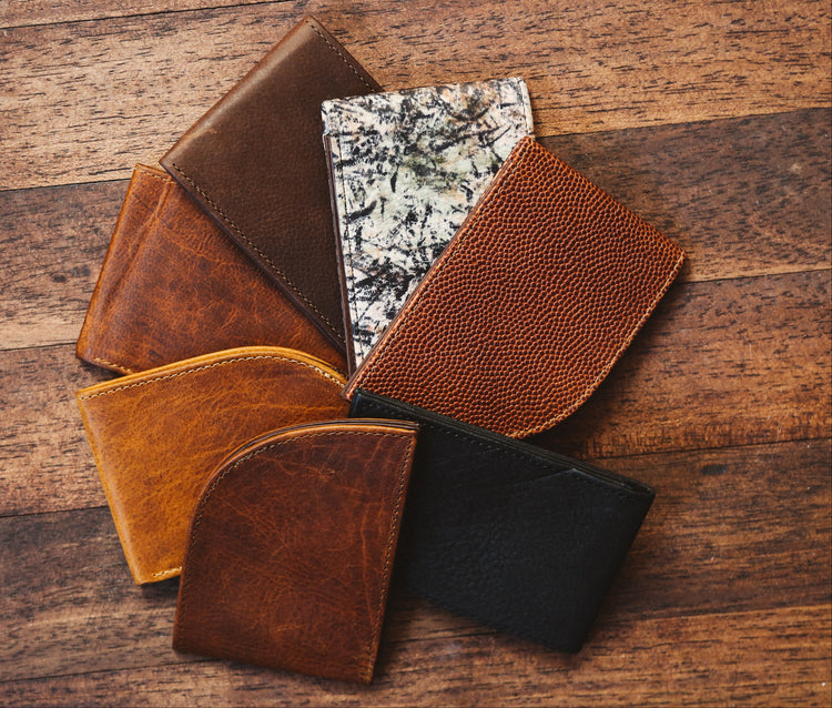 A group of leather wallets on a wooden floor.