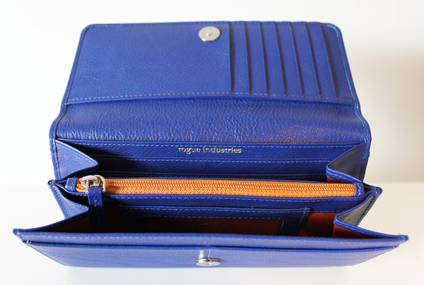 A blue Campobello RFID Blocking Clutch open on a table, displaying its compartments and a zipped section.