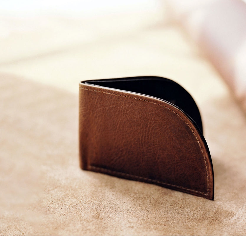 A brown leather wallet sitting on top of a table.