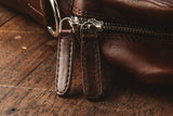 A brown Rogue Industries Katahdin Leather Briefcase with a removable strap on a wooden table.