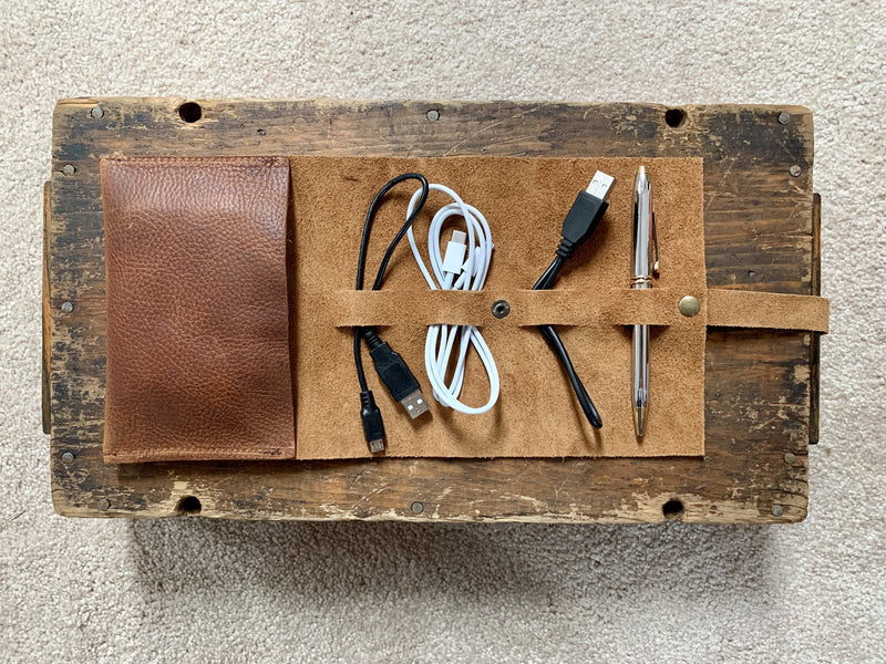 A Rogue Industries top-grain leather tech organizer with cables, a pen, and a pencil inside.